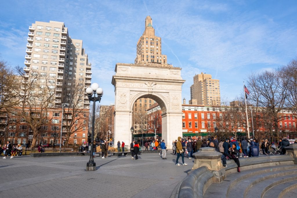 Photo of Washington Square Park in NYC with the arch visible in the middle of the photo.