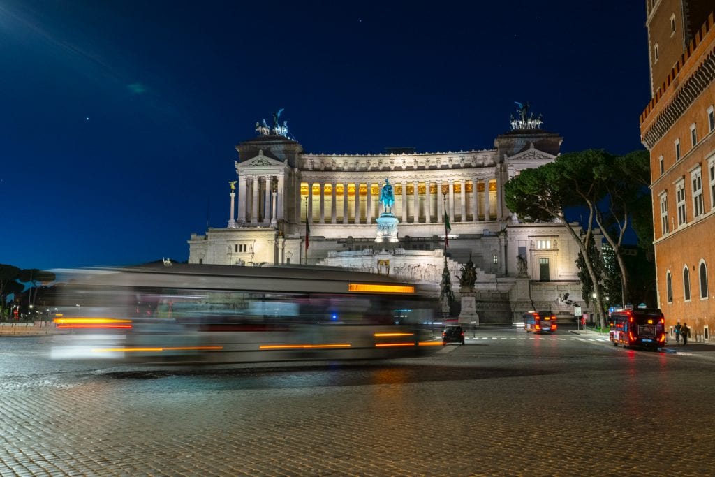 Altar of the Fatherland in Rome at night with a blurred bus passing in front of it