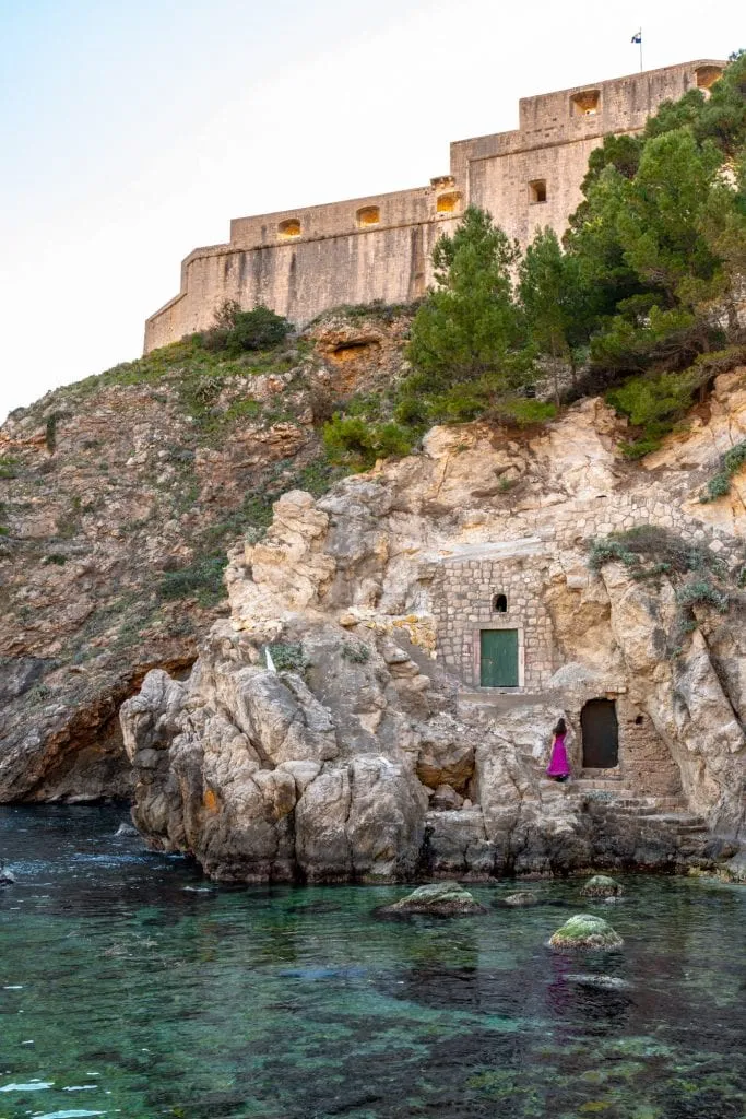 kate storm in a purple dress in front of west harbour doors during a day in dubrovnik