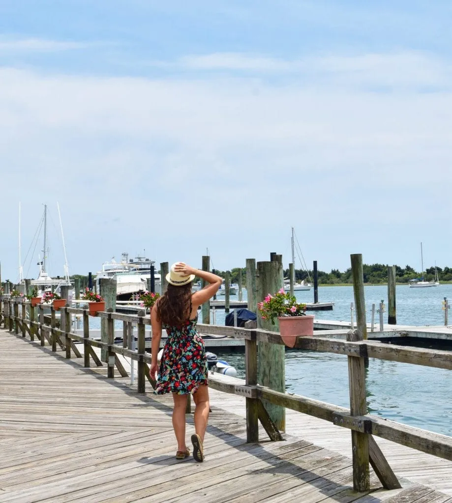 Kate Storm in a floral dress on a boardwalk, one of the best things to do in Beaufort NC, with sailboats in the background