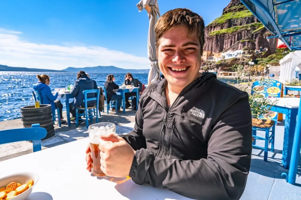 jeremy storm in a black jacket drinking a beer at the fira old port in a blue chair