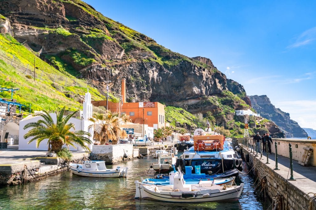 Boats in harbor at Fira's Old Port with cliffs of the island in the background