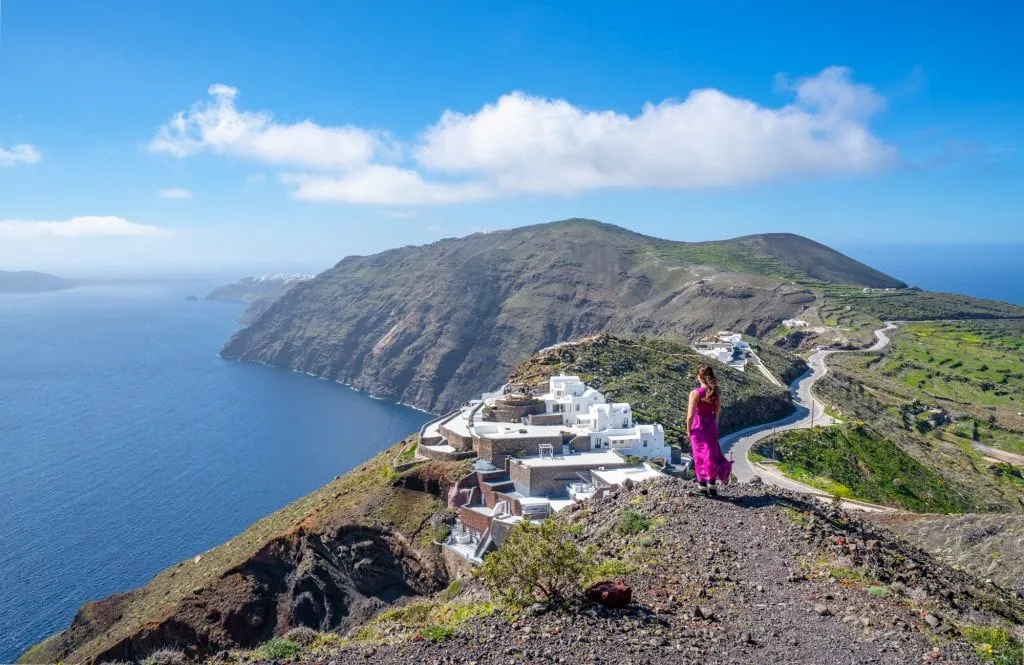 kate storm in a pink dress overlooking Caldera views while hiking from Fira to Oia, one of the best things to do in santorini greece