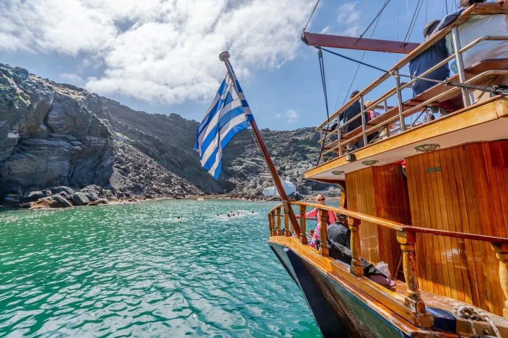 Tourist boat with Greek flag at volcano hot springs, 3 days in Santorini itinerary