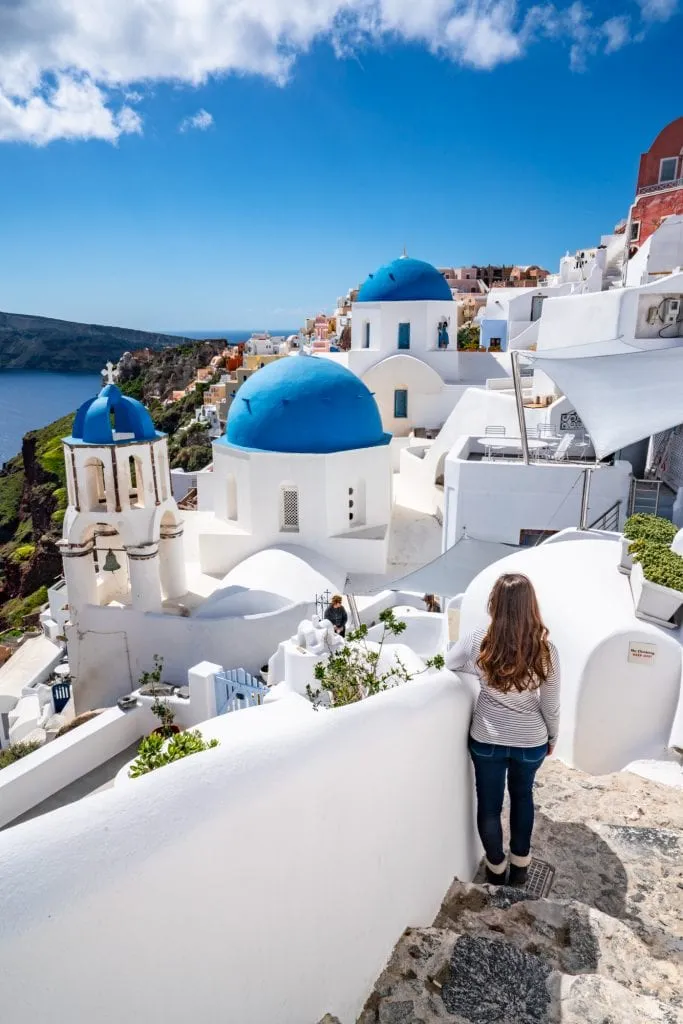 kate storm standing in front of 3 blue domes on Santorini, Honeymoon in Santorini