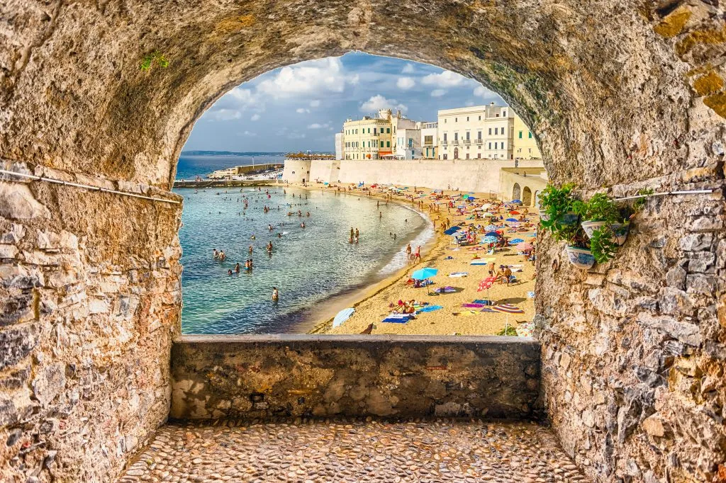 beach of gallipoli puglia as seen through a stone wall, one of the best italian coastal towns