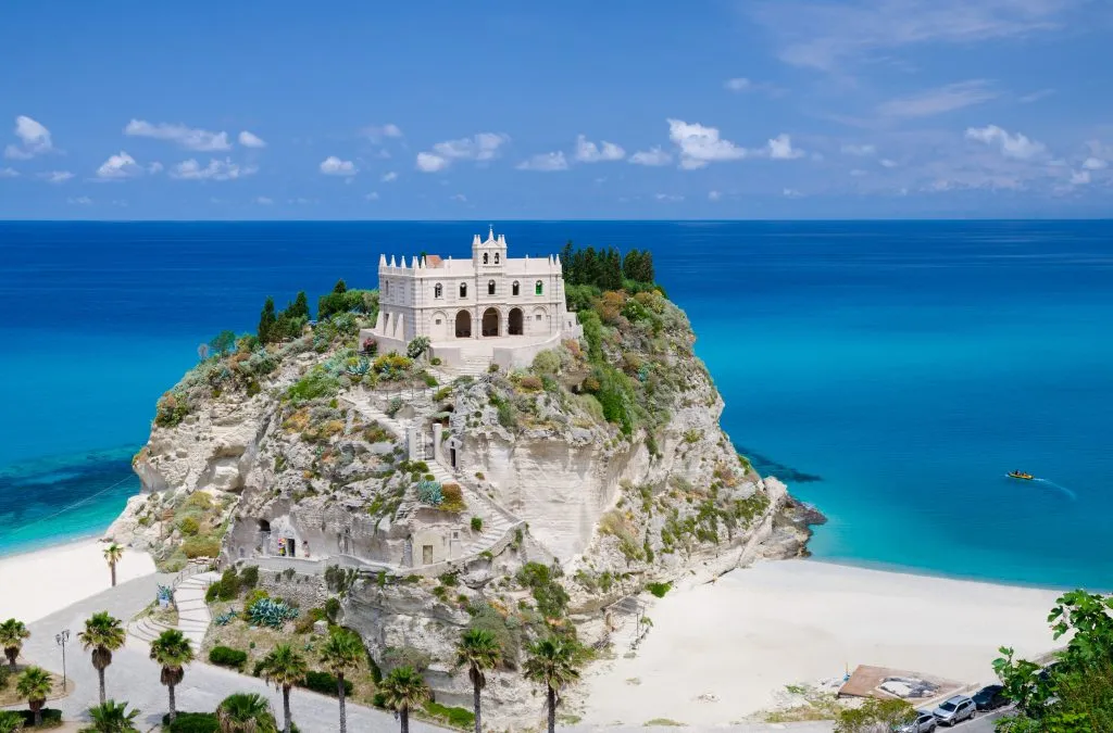 white castle of tropea italy sitting on an outcropping of rock with the sea in the background, one of the best seaside towns in italy