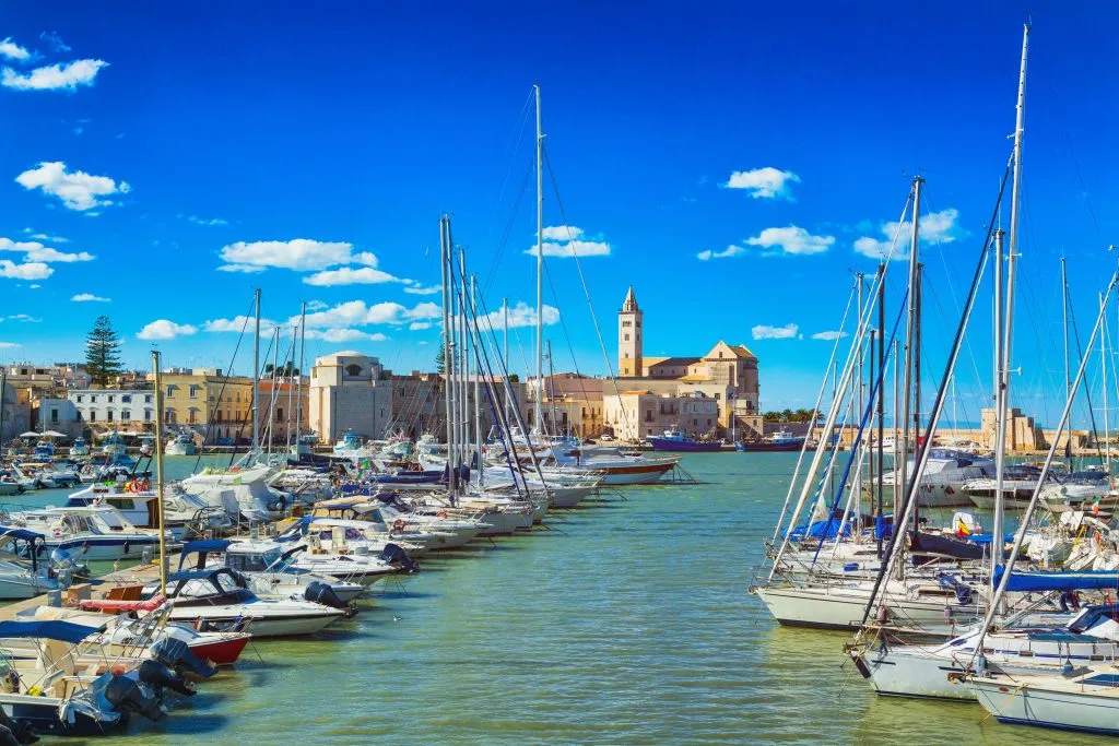 harbor of train puglia with sailboats in the foreground, one of the best italy coastal towns