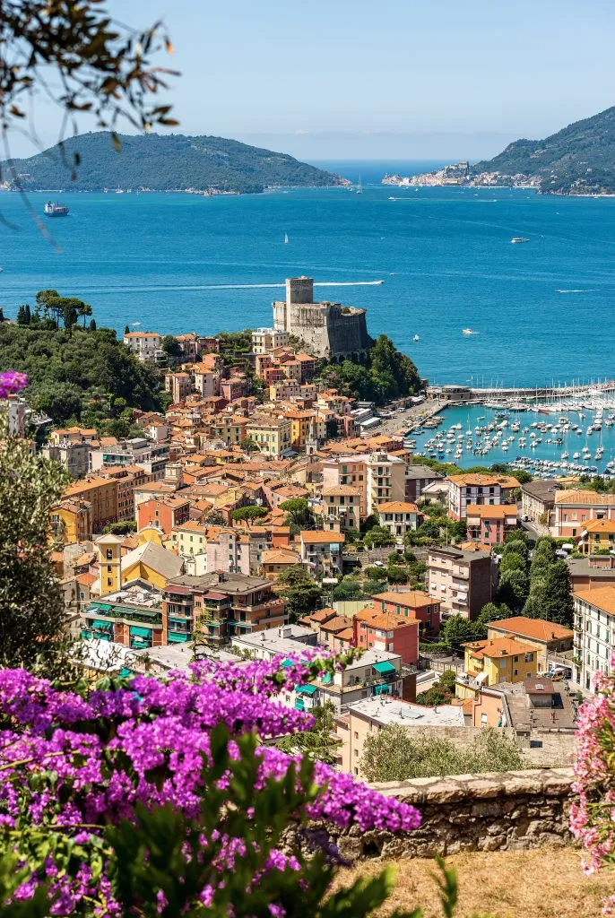 view of lerici italy from above with purple flowers in the foreground and the sea in the background