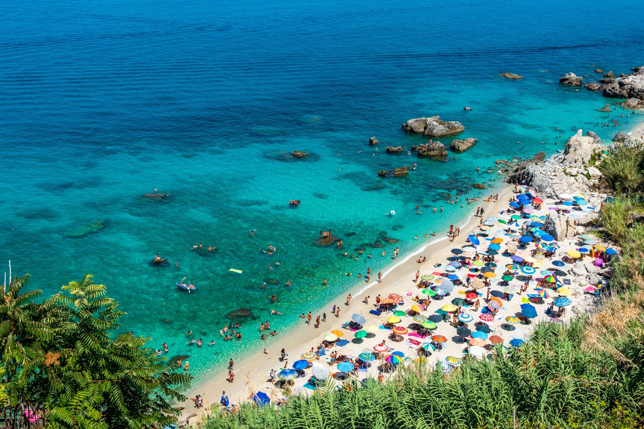 crowded white beach in italy surrounded by the water in tropea, one of the best beach towns in italy