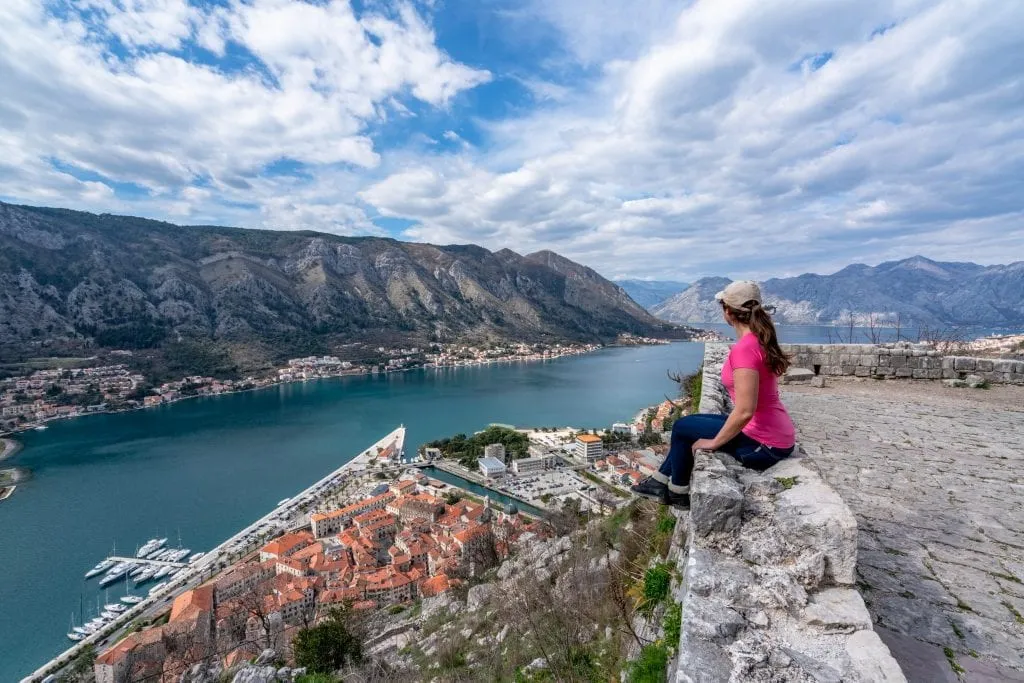 Kate Storm in a pink shirt climbing San Giovanni Fortress: Best Things to Do in Kotor Montenegro