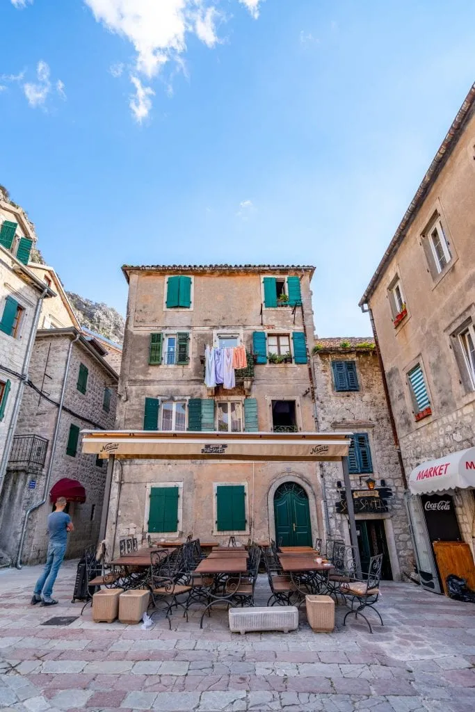 Tan Building with blue shutters and laundry hanging outside in Old Town of Kotor, Best Things to Do in Kotor Montenegro