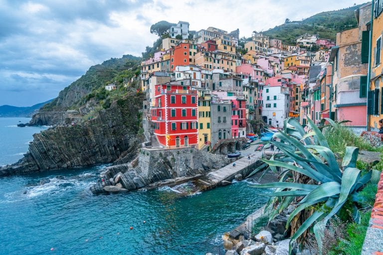 View of Riomaggiore at sunset with the sea in front of it--one of our Cinque Terre tips is to watch at least one sunset in the villages if you can!