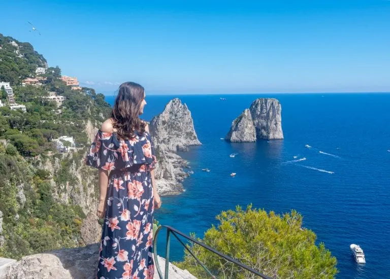 kate storm in a floral dress overlooking the coast of capri, one of the top places to visit during summer in italy