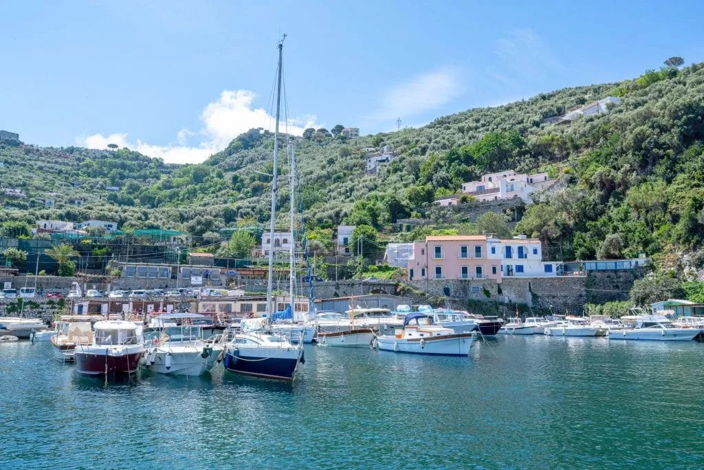 Sailboat in a small harbor along the Amalfi Coast, with other, smaller boats in the background.