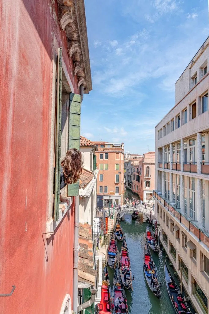 flicka tittar ut genom fönstret på Hotel Lisbona, rekommenderas hotell för 2 dagar i Venedig