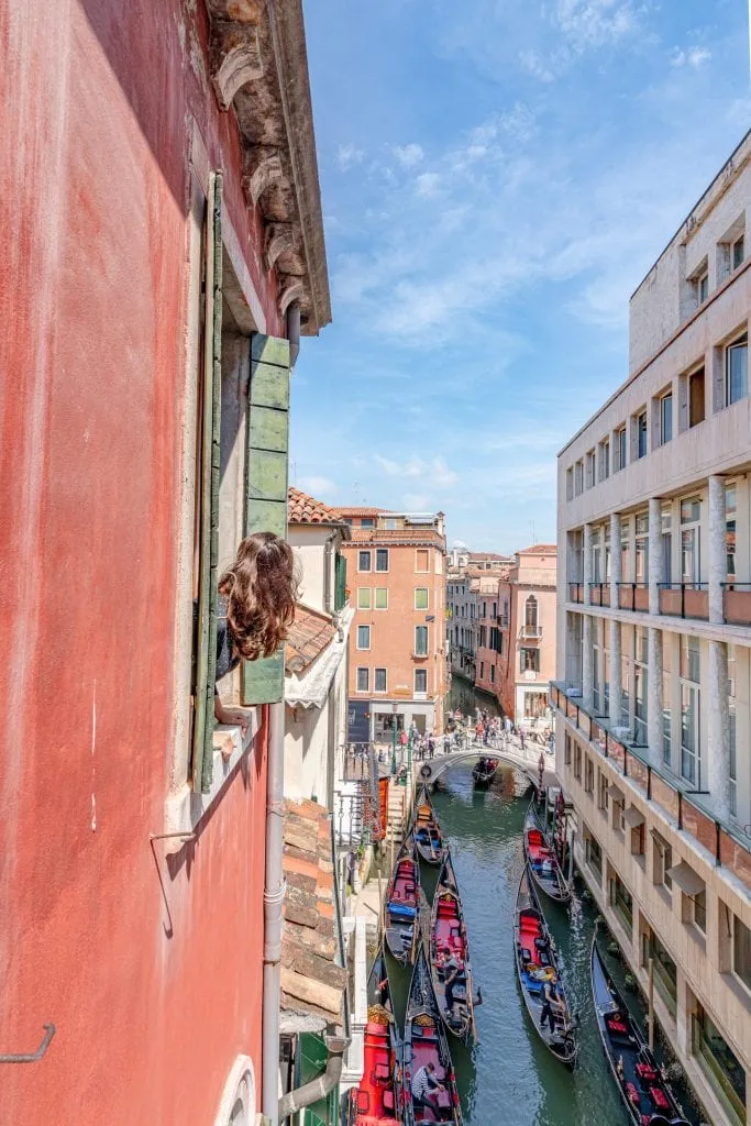 Girl looking out the window of Hotel Lisbona, recommended hotel for 2 days in Venice