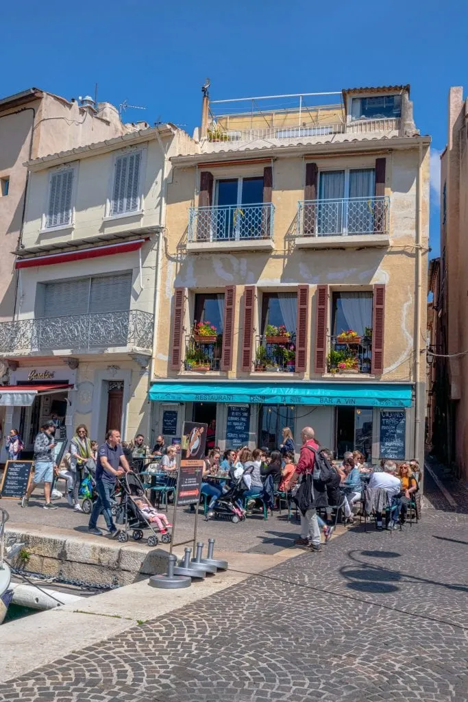 Busy restaurant in Port de Cassis with diners sitting at tables on the sidewalk