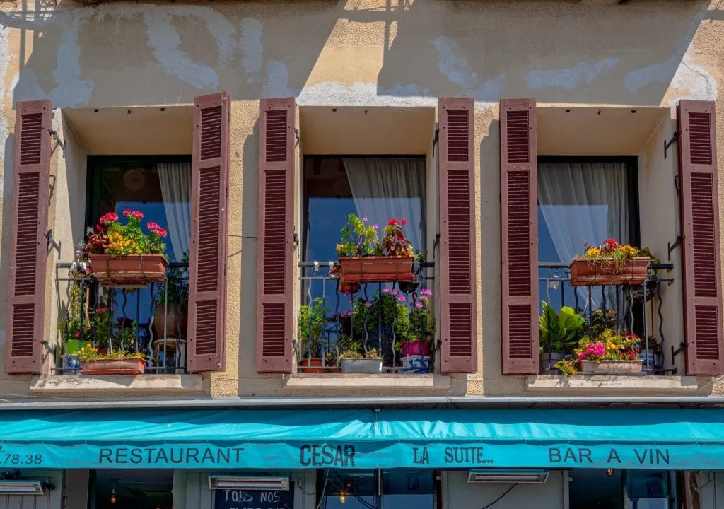 3 windows with red shutters and a turquoise banner underneath them in Cassis France