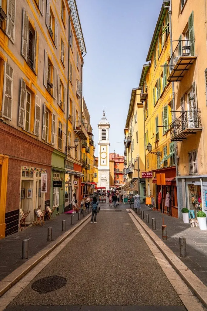 Colorful street in Nice, France, with yellow buildings on both sides.