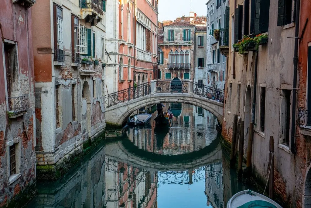 Footbridge reflecting into a quiet canal in Venice. Venice is a fascinating city and home to some very interesting facts about Italy