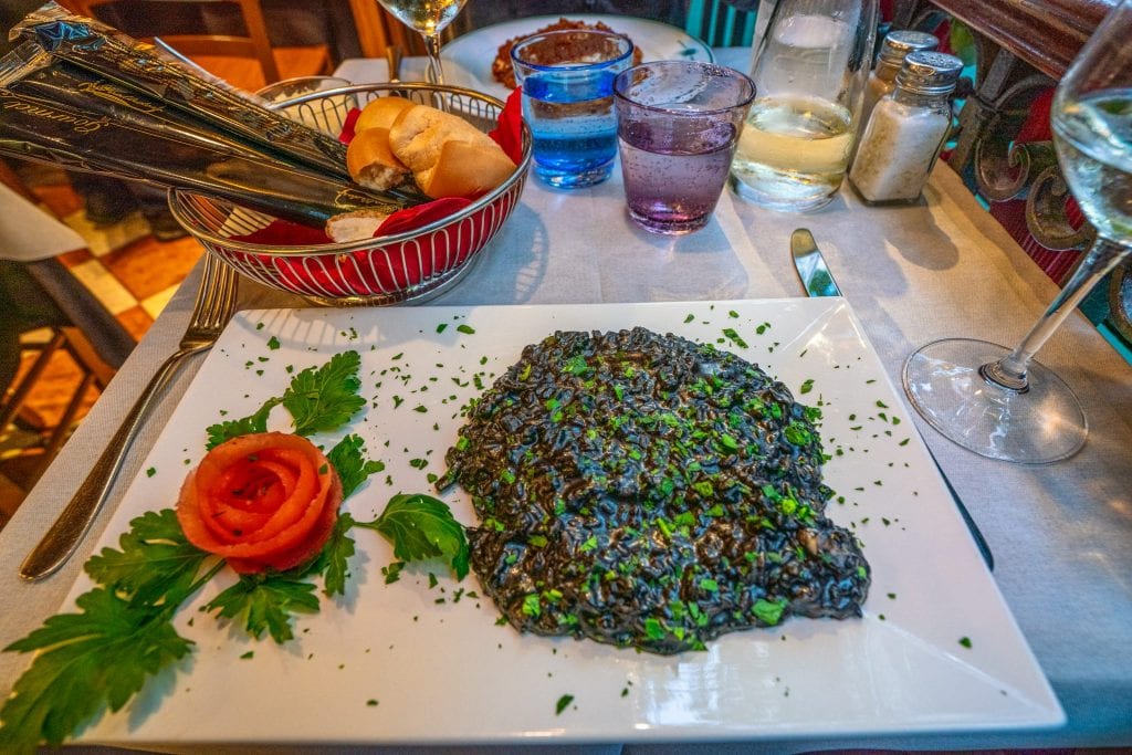 a plate of squid ink risotto in venice italy restaurant, as enjoyed for dinner in italy