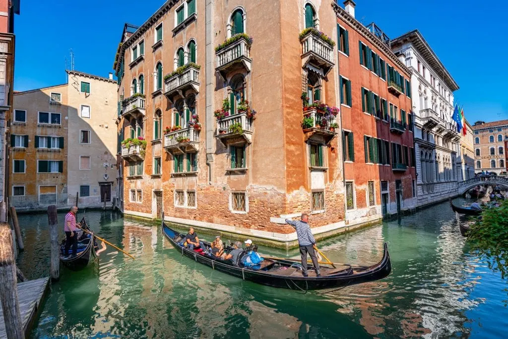 Gondola being steered around a corner between two canals in Venice. Venice's canals were used for many incredible scenes in movies that take place in Italy