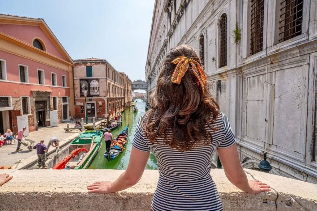 Kate in a striped dress in Venice looking toward the bridge of sighs--definitely worth seeing during one day in Venice! Kate has a yellow ribbon in her hair.