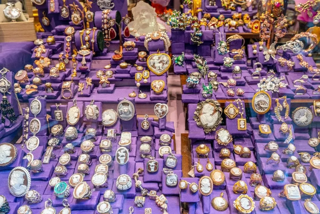 Display of brooches for sale against a purple background in Venice