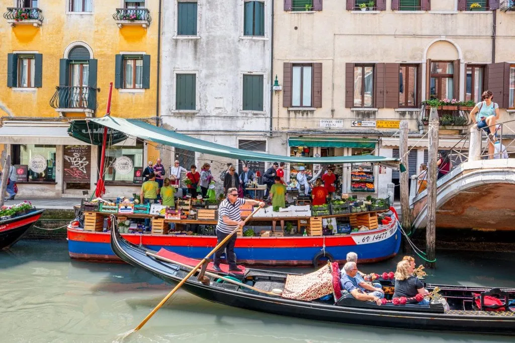 Vegetal barcaça em Dorsoduro, em Veneza, com uma gôndola passando em frente a ela