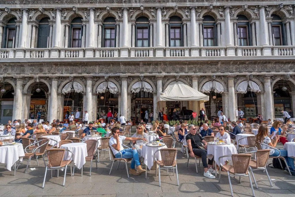 tourists enjoying coffee at an outdoor cafe in famous venice square st marks