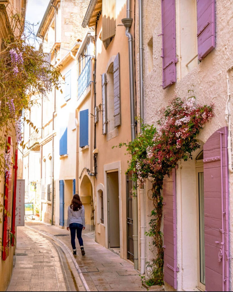 kate storm walking down an empty side street in saint remy de provence france with colorful shutters lining the buildings