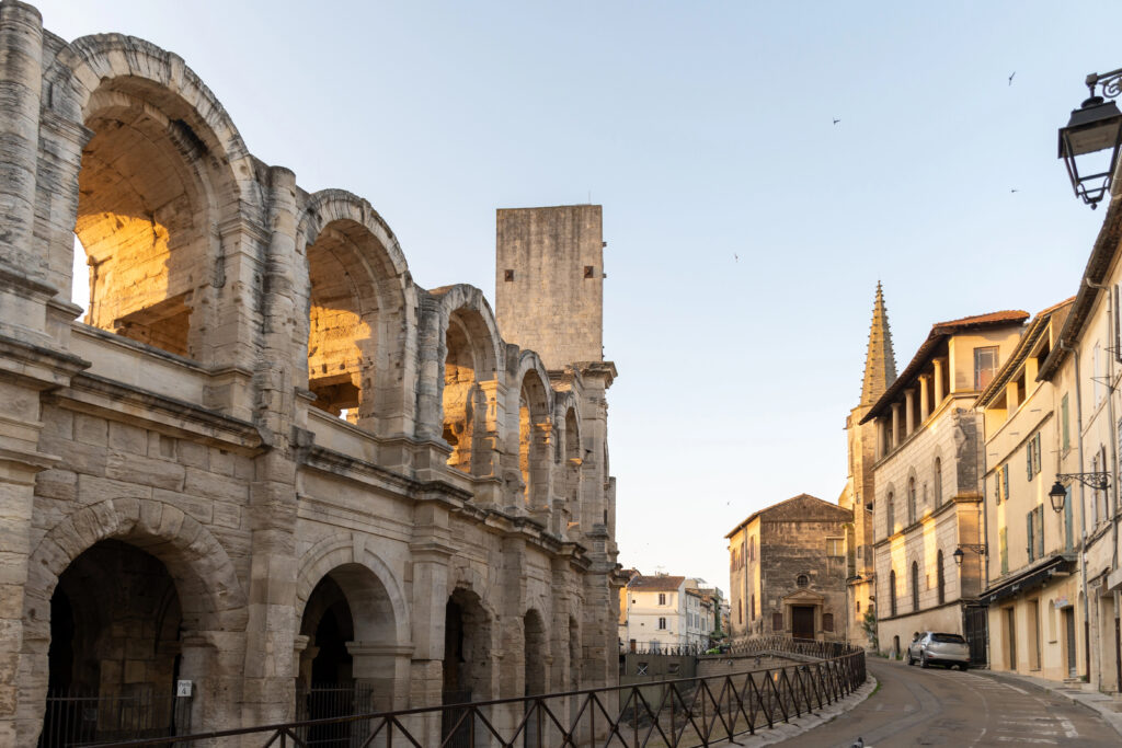 photo of arles france near sunset with amphitheatre on the left and town buildings visible on the right