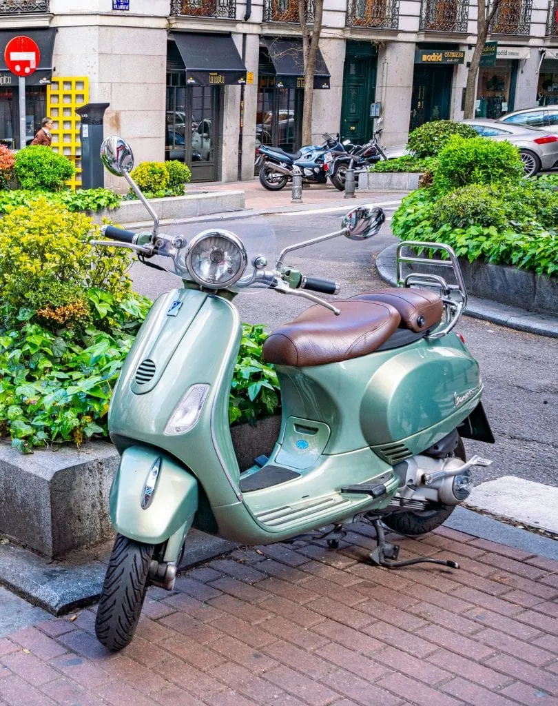 Teal Vespa parked on the corner of a street in Madrid Spain