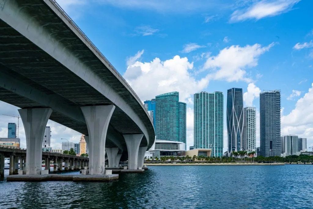 A Miami causeway is on the left of the photo, and a piece of the skyline on the right. The causeway is built over water, visible on the bottom of the photo.