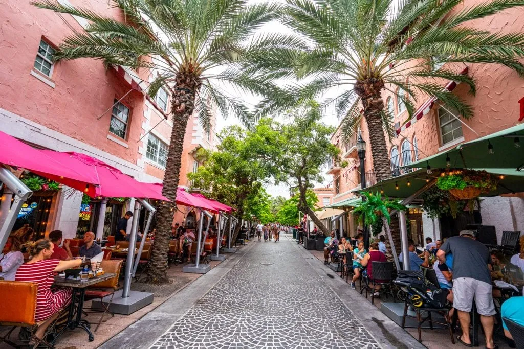 Espanola Way in Miami: the pedestrian street in the center is empty and cobblestone. The street is framed by palm trees and restaurants.