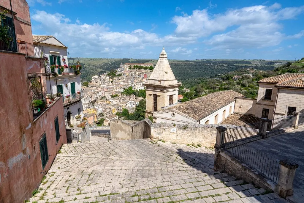 Steep staircase in Ragusa with a church tower on the right and Ragusa Ilba visible in the distance