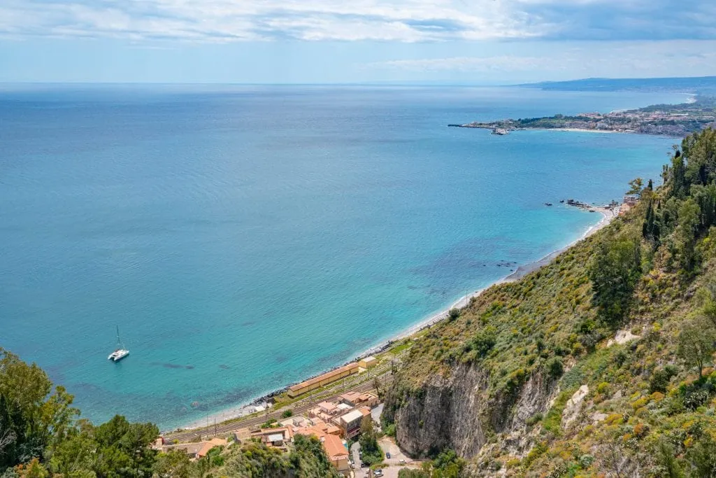 View of Ionian Sea from Taormina Sicily. There's a lone catamaran in the bottom left corner of the photo.