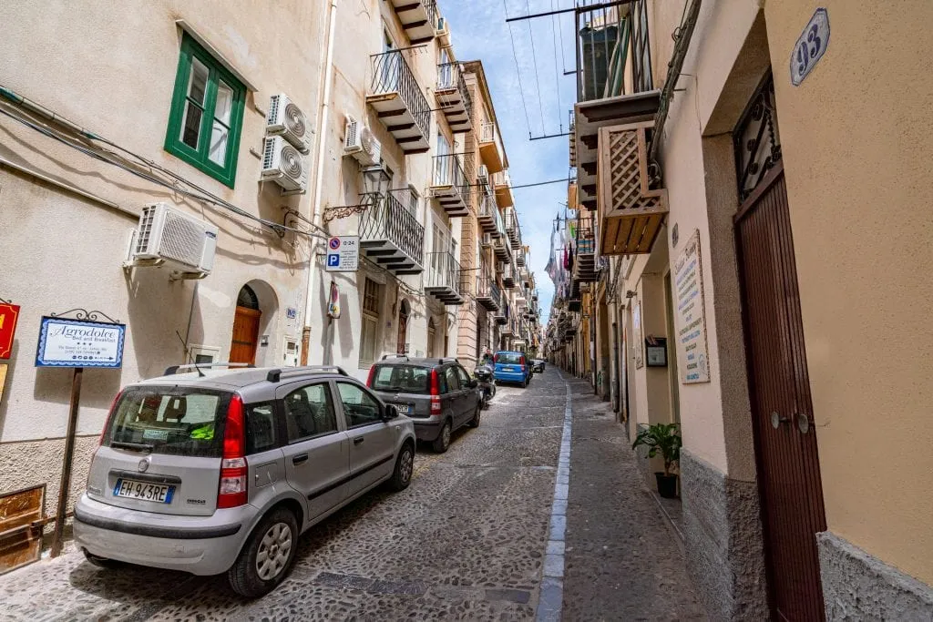 Small street of Cefalu Sicily with cars parked alongside it