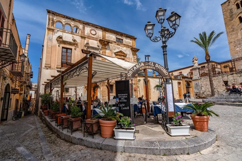 Restaurant with outdoor tables shaded by awnings outdoors in Piazza Duomo in Cefalu, as seen on a Sicily road trip