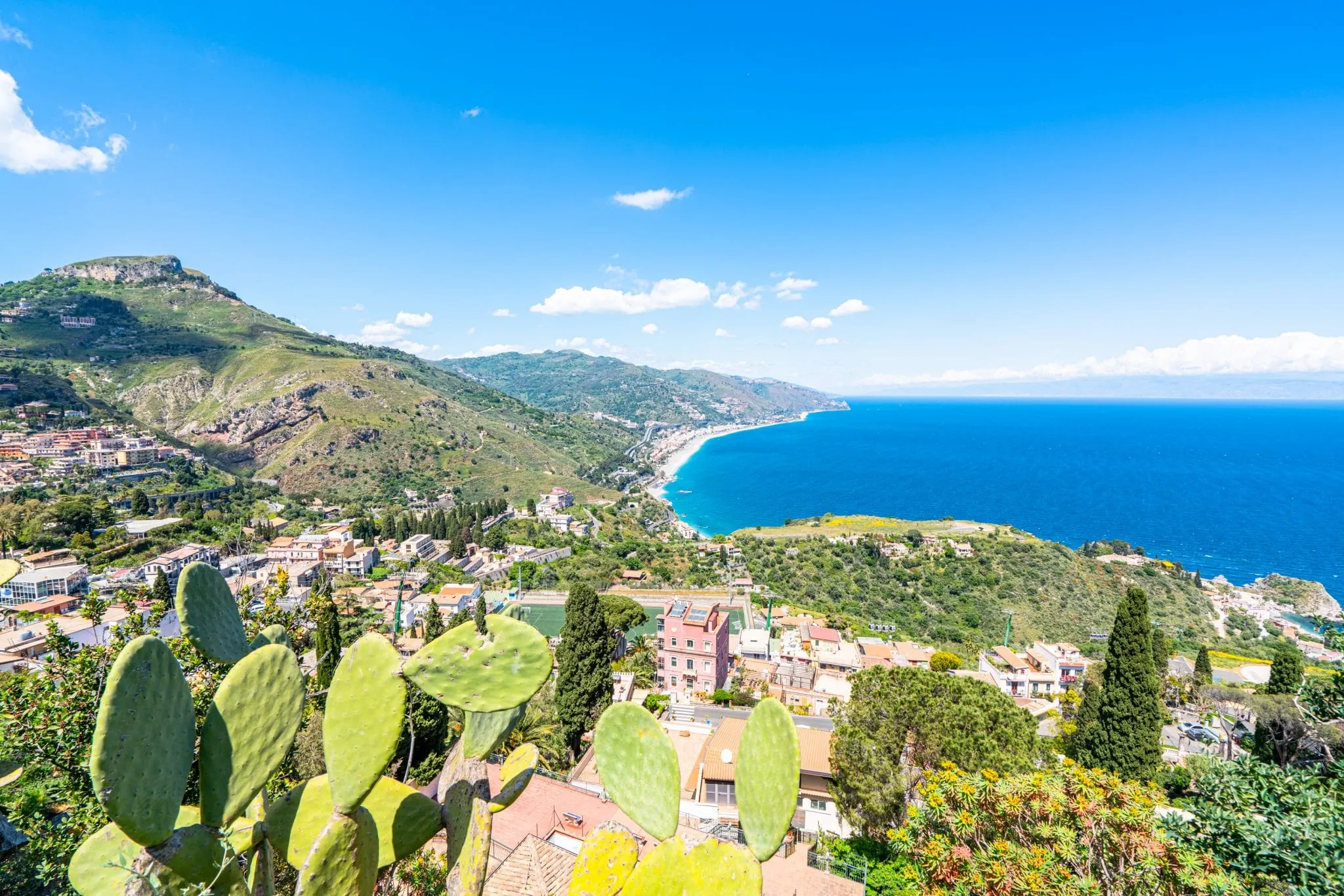 Photo of the Ionian Sea as seen from Taormina. There are cacti in the foreground of the photo.