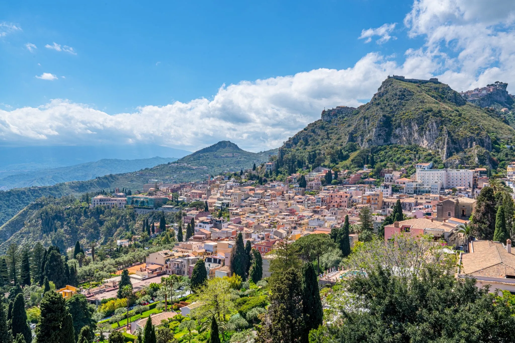 View of Taormina as seen from grounds of the Greek theatre. You can see the bottom of Mount Etna, the peak is covered by clouds.