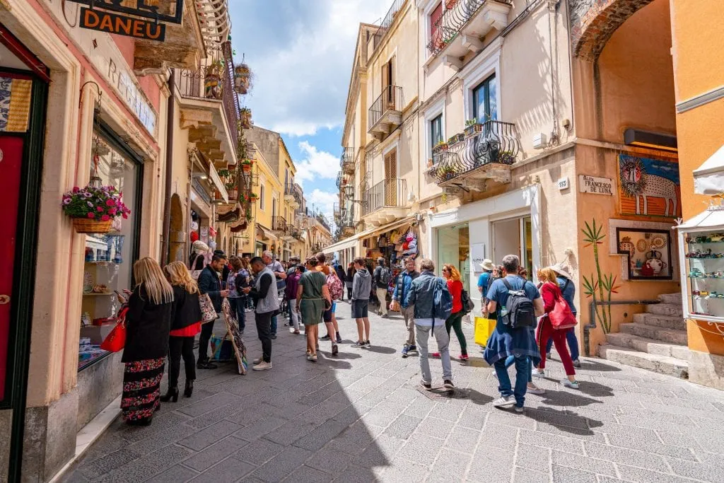 Photo of Corso Umberto in Taormina Sicily. There's a crowd of people in the street.