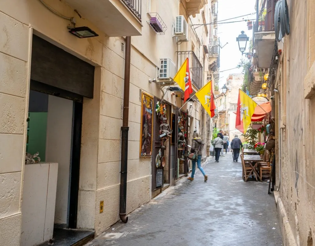 small street in Syracuse Sicily with flags outside the shop windows