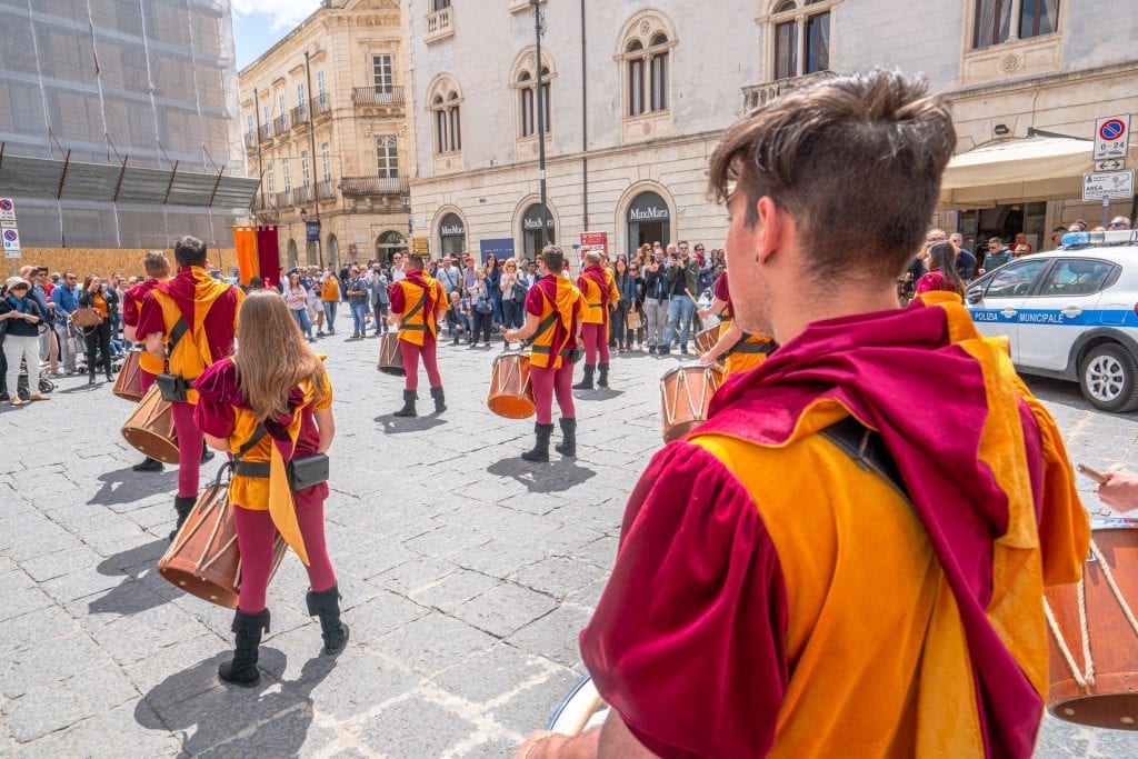 Parade in Syracuse Sicily with a drummer in the foreground looking away from the camera