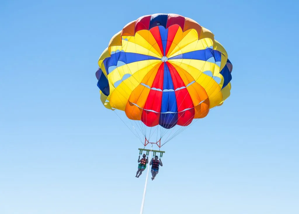 two people parasailing in a multi colored parasail