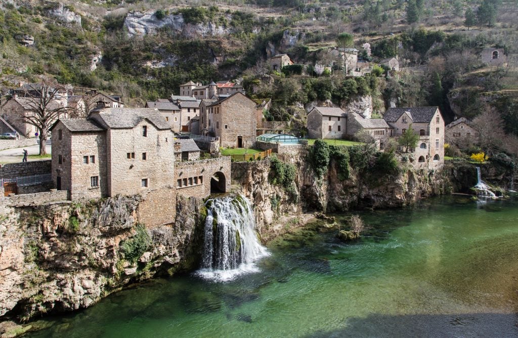 village is gorges du tarn france with a waterfall spilling into the river