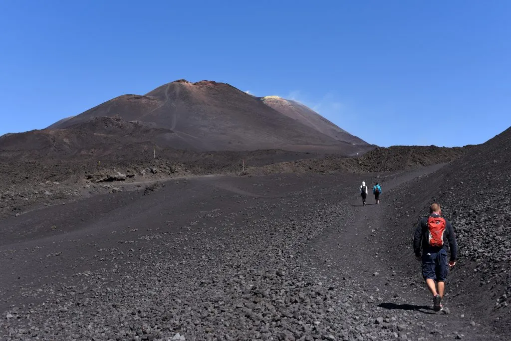 people hiking on the barren landscape of mount etna sicily