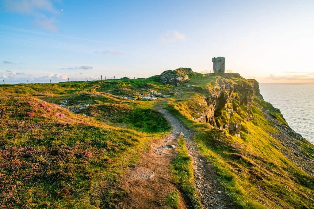  udsigt over Hags hoved med Moher-tårnet til højre ved solnedgang-absolut en oplevelse, der er værd at have, når man besøger Cliffs of Moher i Irland!