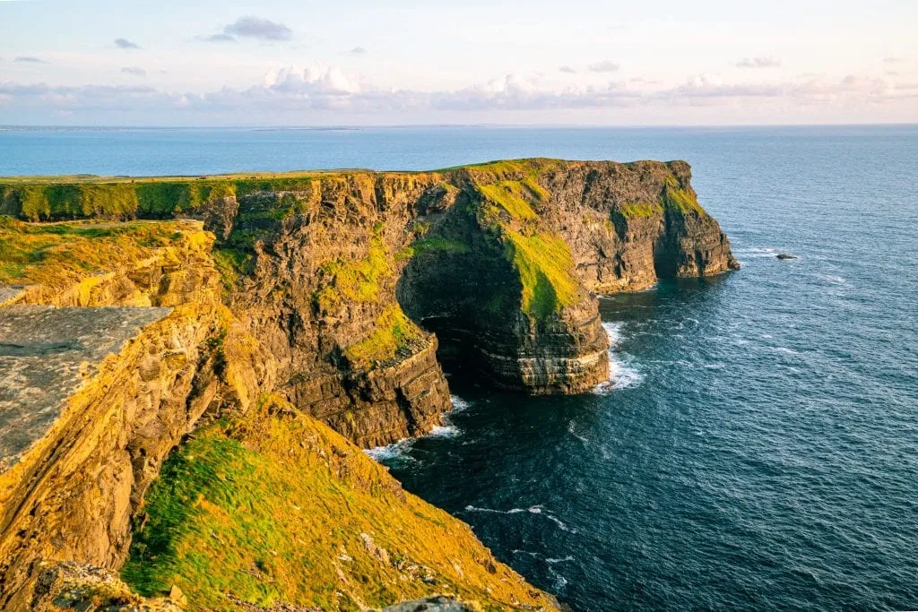 Section of the Cliffs of Moher lit up as a golden color from the sunset